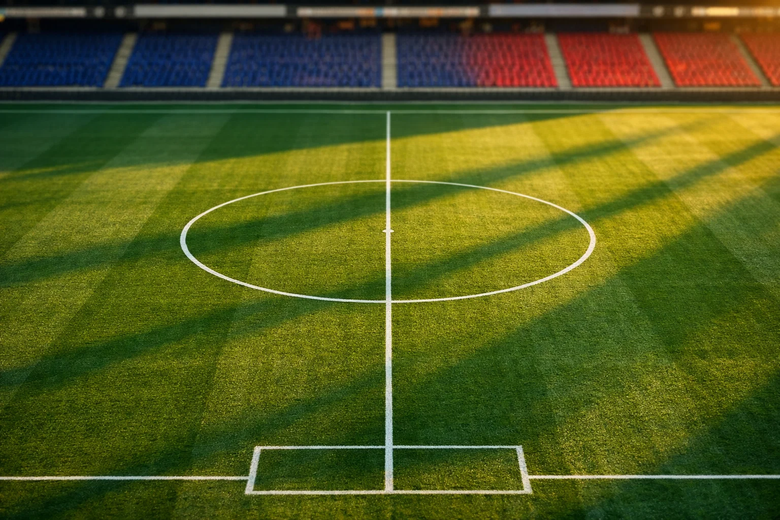 Vue aérienne d'un terrain de football français moderne avec pelouse impeccable et tribunes aux couleurs bleu et rouge